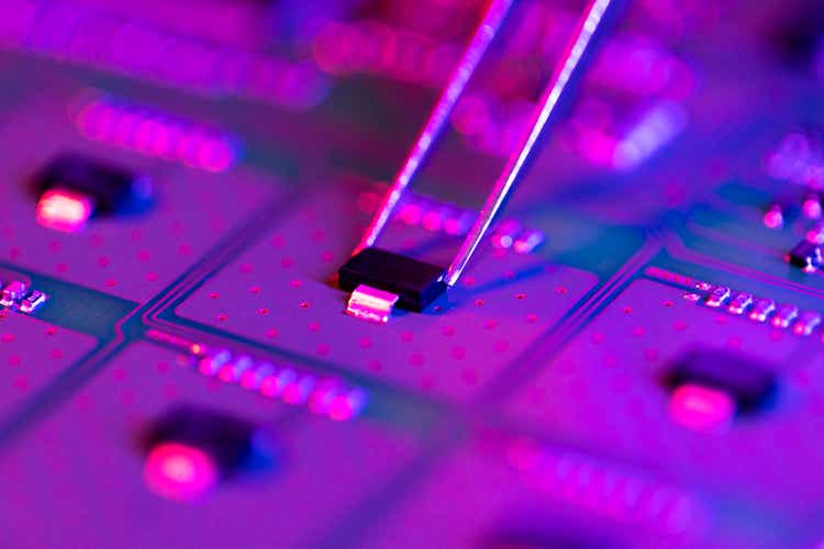 Electronic technician holding tweezers and assemblin a circuit board