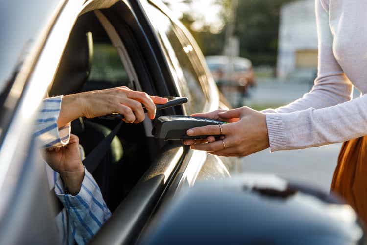 A customer pays for their order via smartphone during curbside pickup.