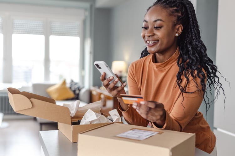 Beautiful African-American woman using online paying services on smart phone