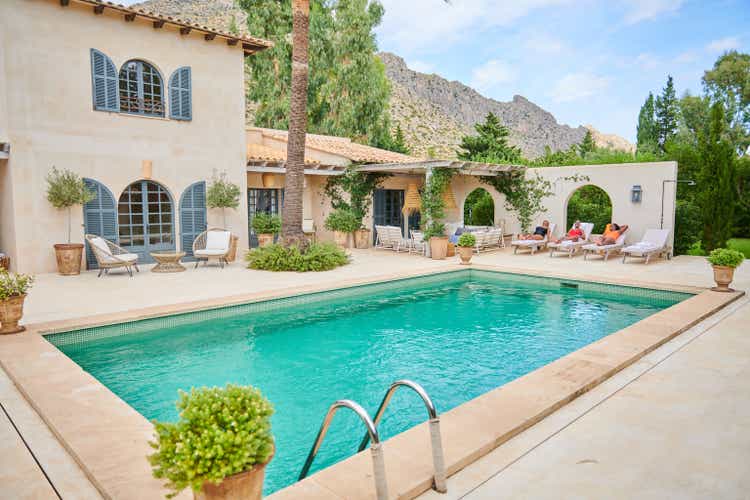 Luxury holiday villa. Three women lying on sun loungers.