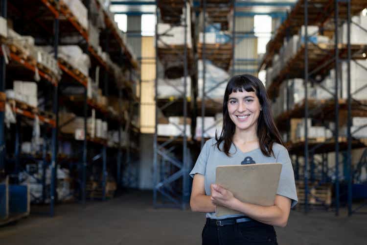 Happy woman working at a distribution warehouse as logistics manager