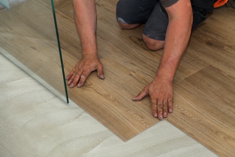 Close up shot of a worker installing new vinyl tile floor