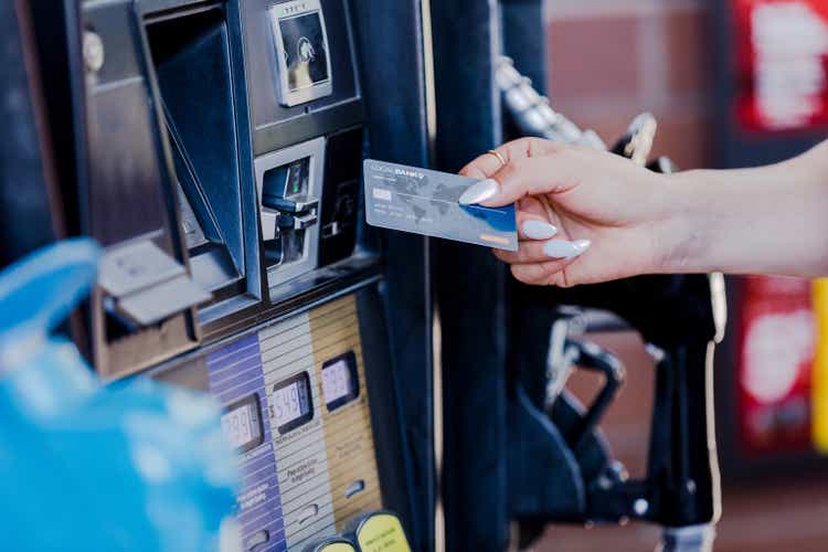 Focus on manicured female hand holding credit card at pump