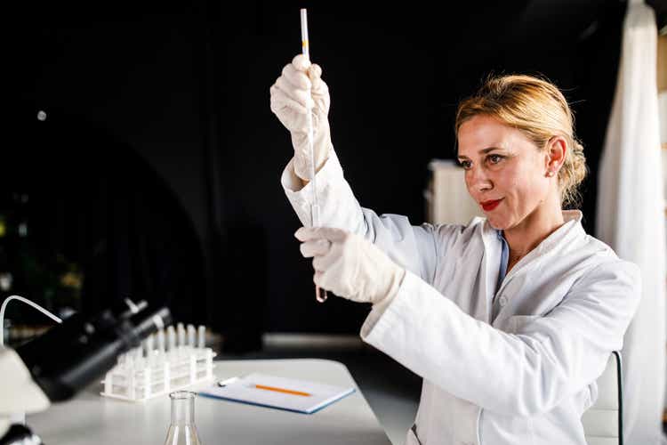 Scientis taking a sample out of a test tube, with a pipette