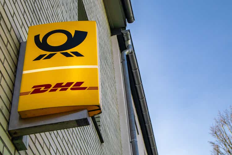a yellow dhl sign attached on a building on the street side