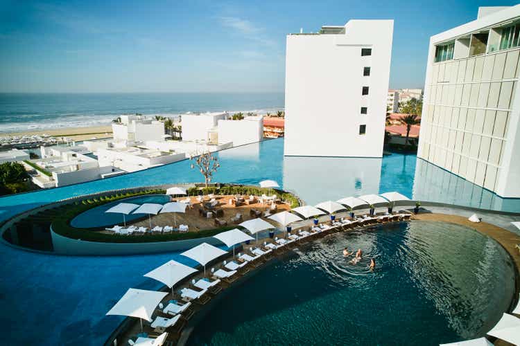 Wide shot aerial view of family playing in pool at tropical resort