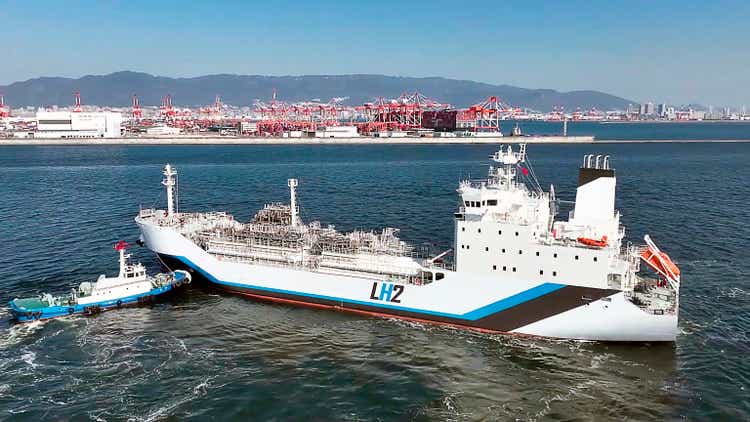 High angle view of the world"s first liquid hydrogen carrier. Entering a seaport and being assisted by a tugboat.