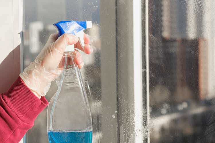 Woman"s hand in a rubber glove holding spray bottle for cleaning windows