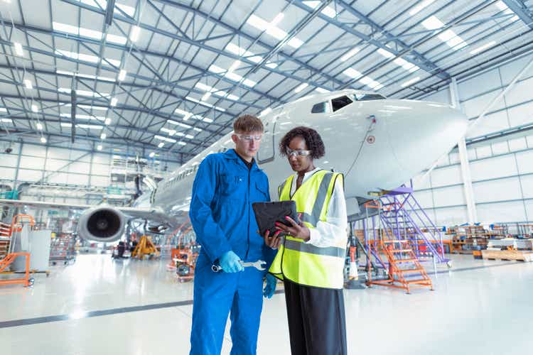 Apprentice aircraft maintenance engineer with supervisor in maintenance hangar