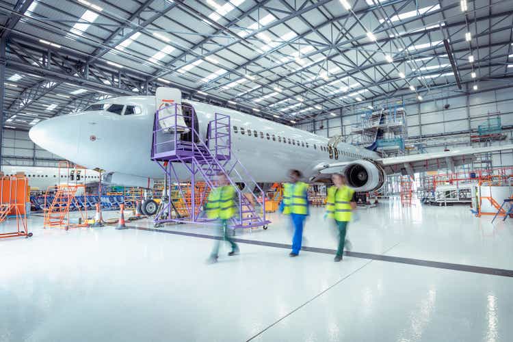 Aircraft maintenance engineers walking past aircraft in maintenance hangar