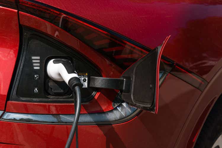 EV charging station for electric car in concept of green energy and eco power produced from sustainable source to supply to charger station in order to reduce CO2 emission. Red electric car charging.