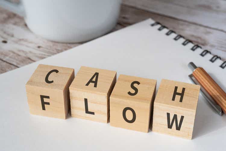 Wooden blocks with "CASH FLOW" text of concept, a pen, a notebook, and a cup.