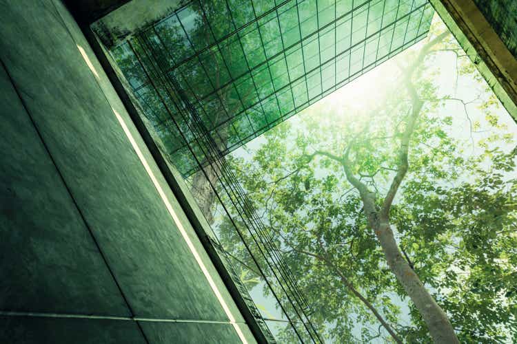 real estate strategic plans Sustainble green building. Eco-friendly building in modern city. Sustainable glass office building with tree for reducing carbon dioxide. Office with green environment. Corporate building reduce CO2.