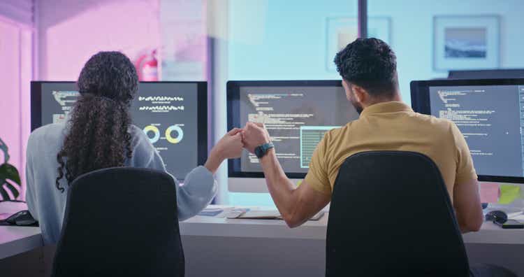 Fist bump, computer and people in office coding software development, digital engineering or programming on desktop monitor screen. Information technology, code and teamwork employees fist hands sign