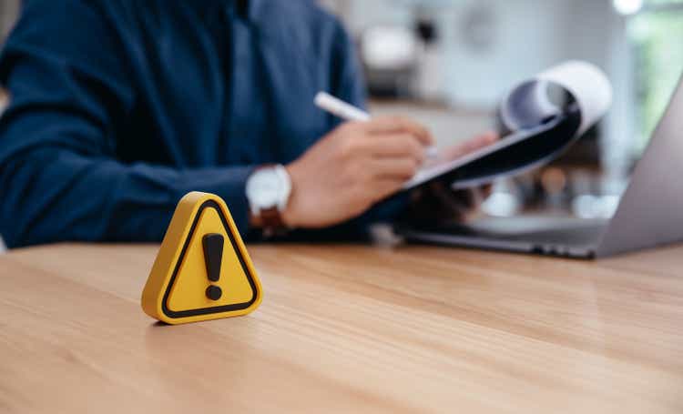 Warning sign on table in front of businessman Caution in investing Economic situation warning, Deflation and inflation concept