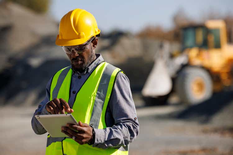 Portrait of male engineer with hardhat using digital tablet while working at construction site