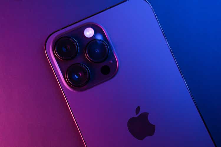 Closeup of iPhone 14 Pro Max Space Black isolated on black background illuminated by blue and pink lights. Low light. 3 featured cameras. Selective focus