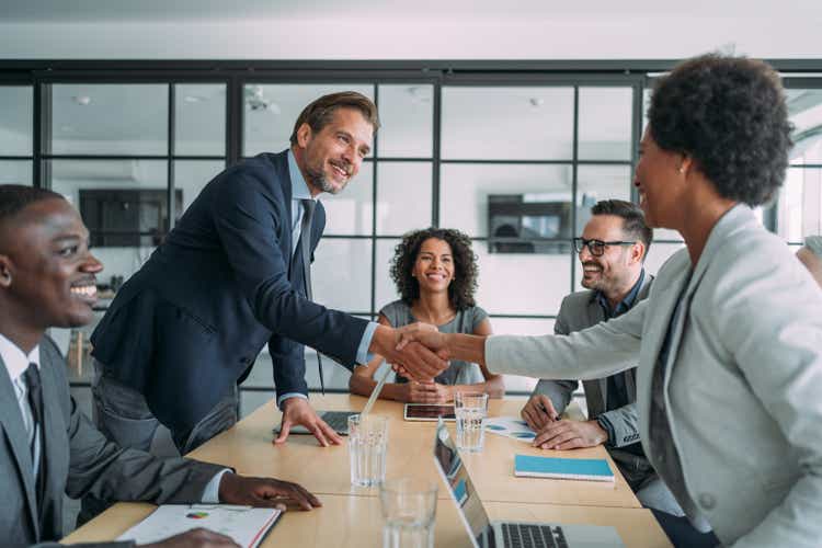 Businesswoman and businessman shaking hands across the table.