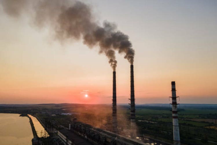 Aerial view of coal power plant high pipes with black smoke moving upwards polluting atmosphere at sunset. Production of electrical energy with fossil fuel concept
