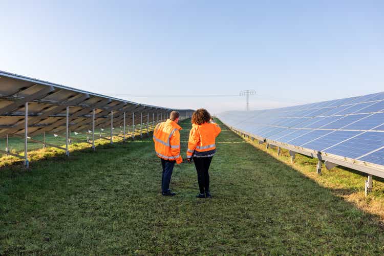 Rear view of a pair of engineers working at a solar farm