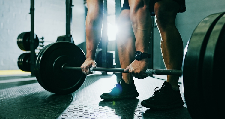 Weight lifting, fitness and athlete hands in a health and wellness gym training for arm muscle. Bodybuilder man power lift weights for strong legs workout in a sports exercise body builder club