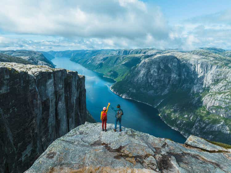 Aerial view of man and woman raising holding arms in mountains in Norway