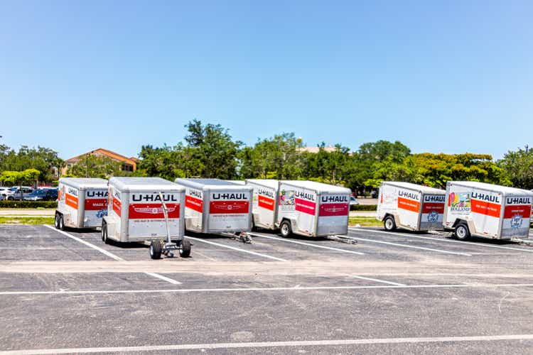 Many parked U-Haul cargo trailers for moving relocation to move home furniture by tow towing in Florida on street road parking