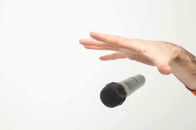 Caucasian male"s hand dropping the mic, stretched hand and a microphone