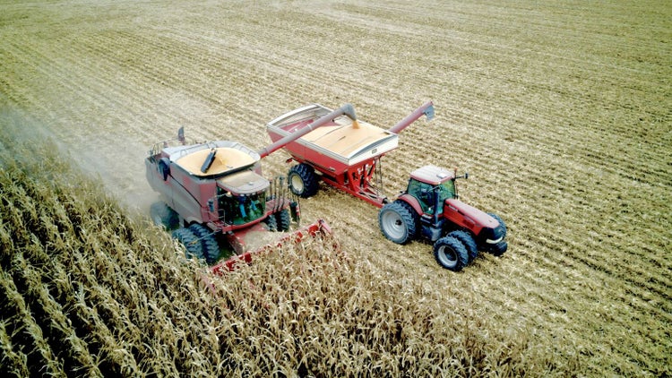 Aerial view of a Case IH combine unloading field corn into a wagon while driving