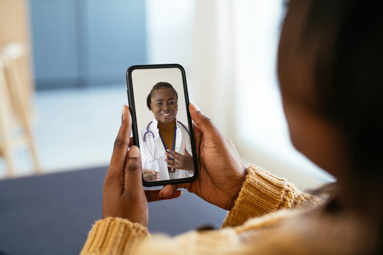 Unrecognisable African woman using digital device during illness, talking to doctor on video call