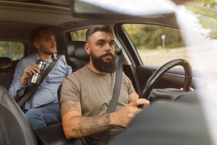 Taxi driver concentrating on the road while driving a businessman to his destination