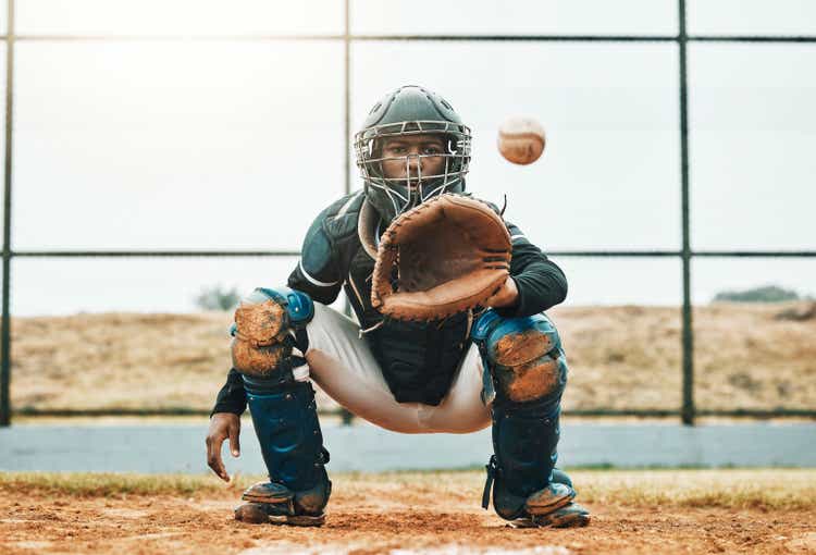 Baseball, catch and sports at the pitch for game, point or score with the ball on a field in the outdoors. Black man pitcher with mitt in sport training, exercise and fitness in competitive match