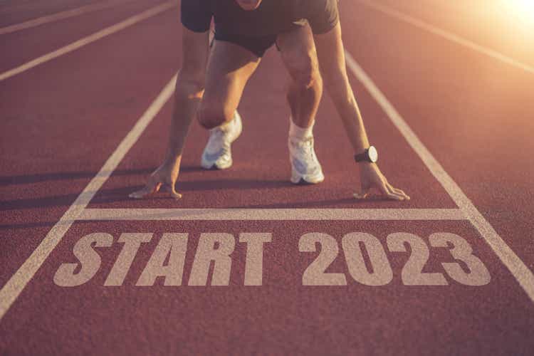 Front view of a man preparing to run on athletics track. Engraved year 2023, goal of success. Get ready for the new year.
