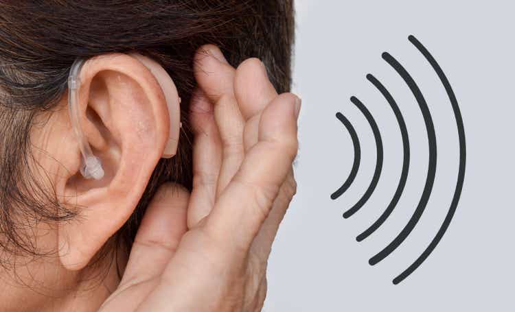 Electronic hearing aid device in the ear of Asian woman with total deafness.
