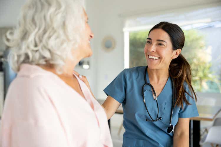 Happy doctor talking to a senior woman on a house call