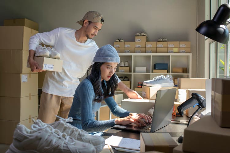 Asian woman and man online seller prepare parcel box and check orders of product for deliver to customer.
