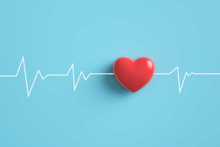 Electrocardiogram pulse trace with red heart on pastel blue background.