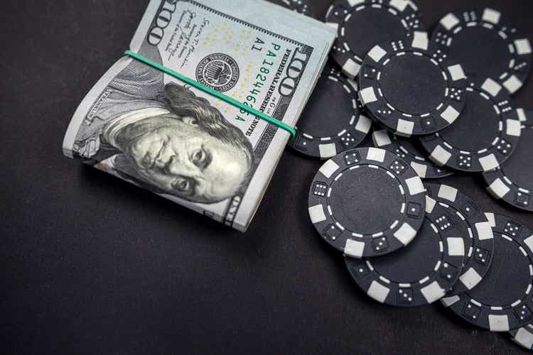 colored poker chips scattered with a roll of US dollars isolated on a black background.