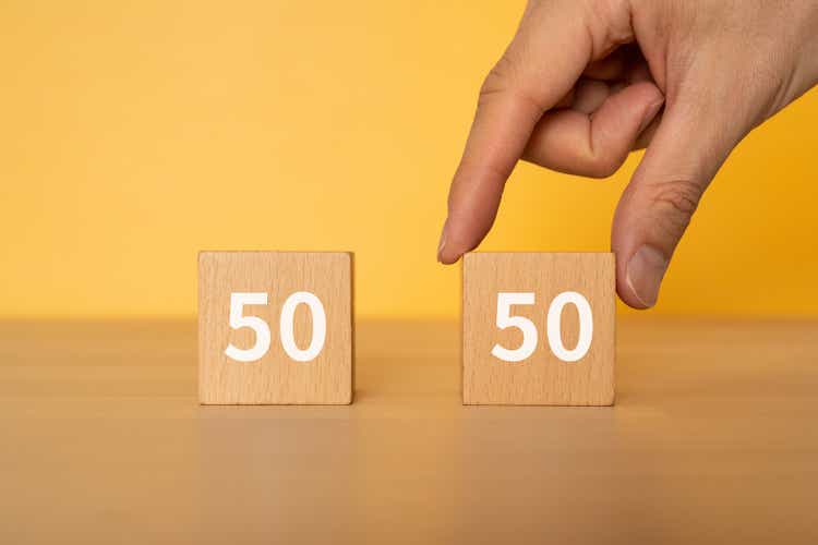 Wooden blocks with "50" and "50" text of concept and a hand.
