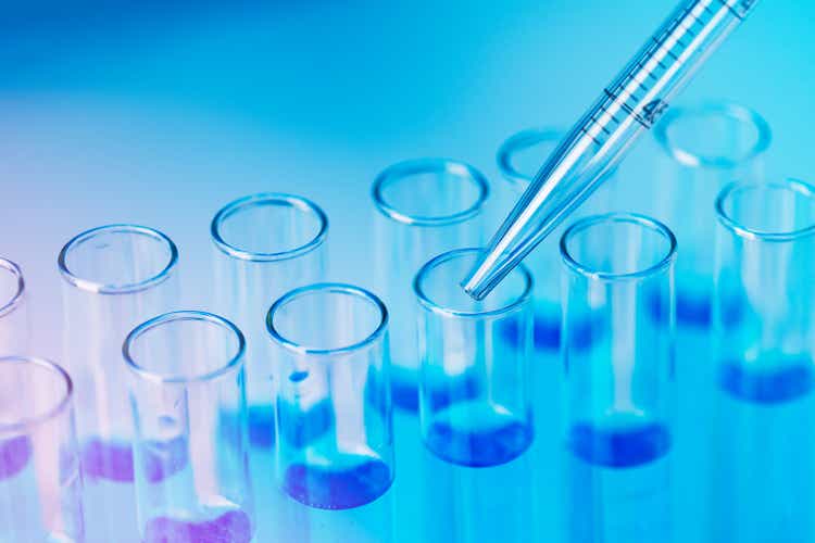 Test tubes with blue liquid water samples and pipette over blue background.
