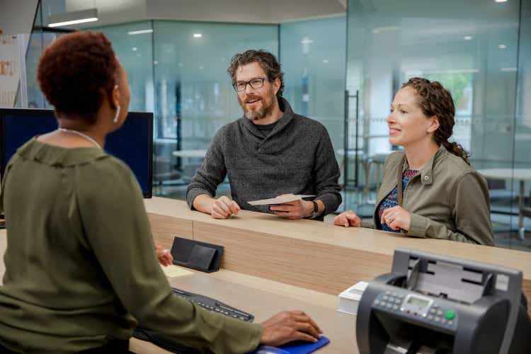 Bank teller talking with couple at bank branch counter