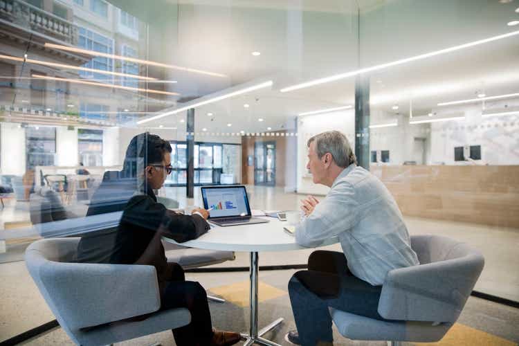 Male loan manager with laptop meeting with client in bank branch office