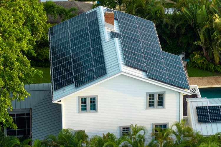 New residential house in USA with roof covered with solar panels for producing of clean ecological electricity in suburban rural area. Concept of investing in autonomous home for energy saving