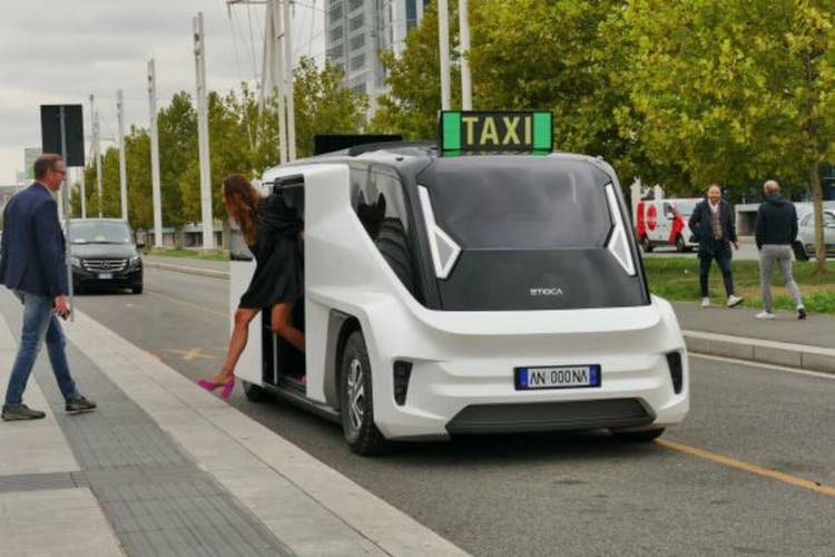 View of a woman getting out from a white ETIOCA full electric minivan taxi