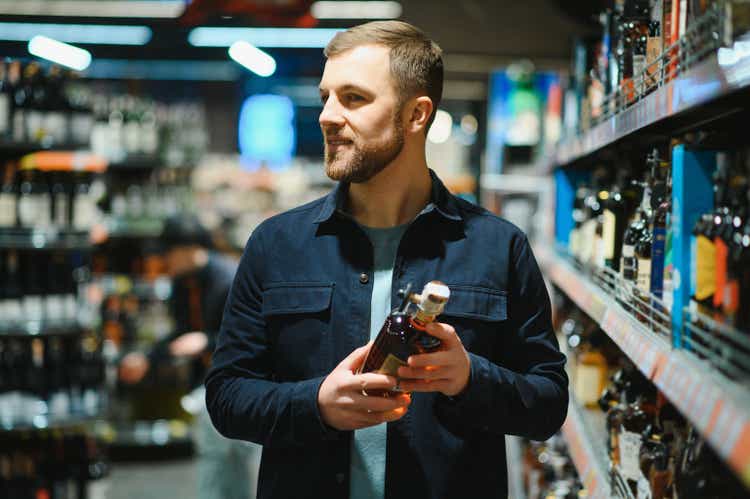 A man takes alcoholic drinks from the supermarket shelf. Shopping for alcohol in the store.