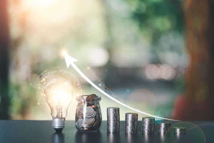 light bulb, a glass jar, and some coins lay on table,finance and banking, fund growth and savings concept, proportional money management to spend effectively,interest growth graph, plan for retirement