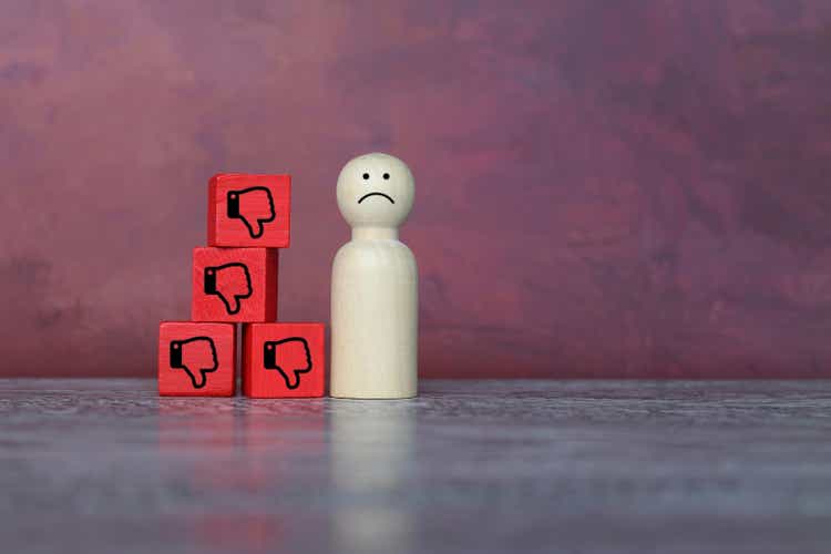 Sad wooden doll and thumbs down icon