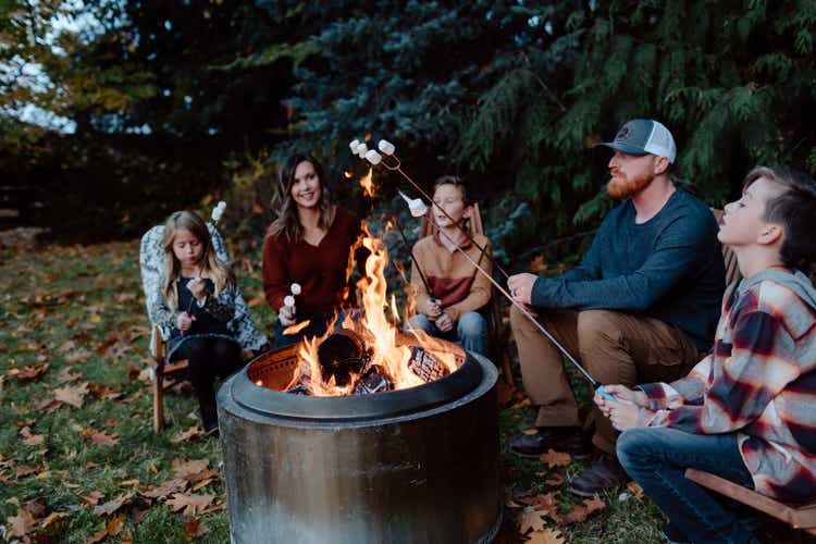 Family roasting marshmallows around fire