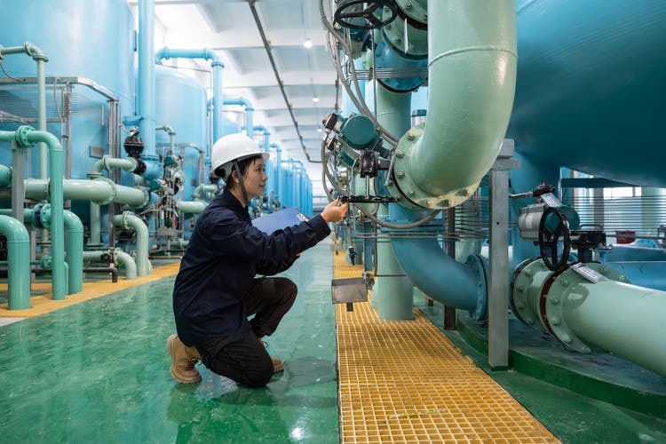 An Asian female prosecutor works in the workshop of a chemical plant