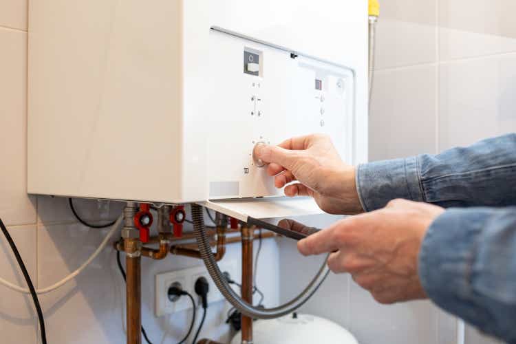 White man lowers the temperature of the gas boiler in his house due to the energy crisis